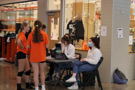 students in orange t-shirts buy homecoming tickets at a table
