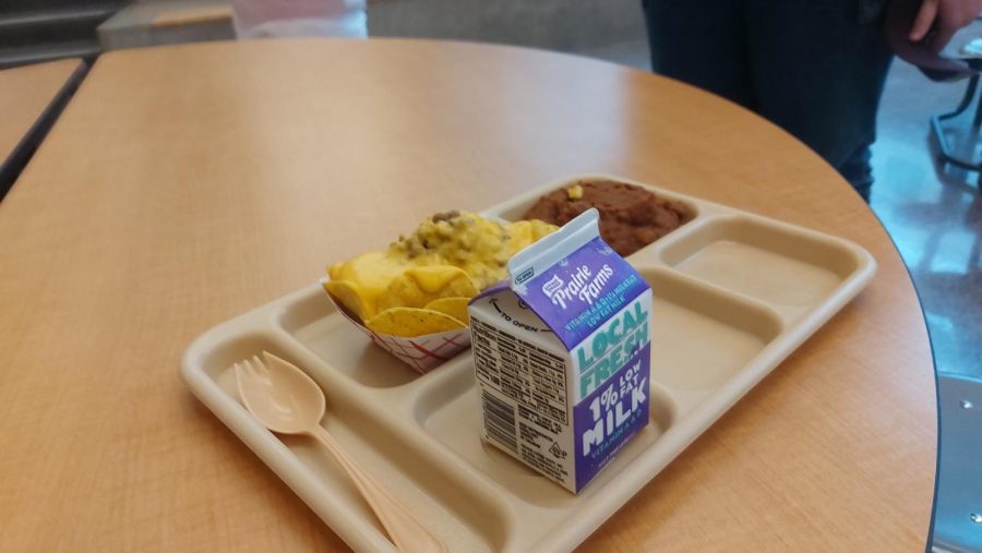 nachos and milk on a beige lunch tray.