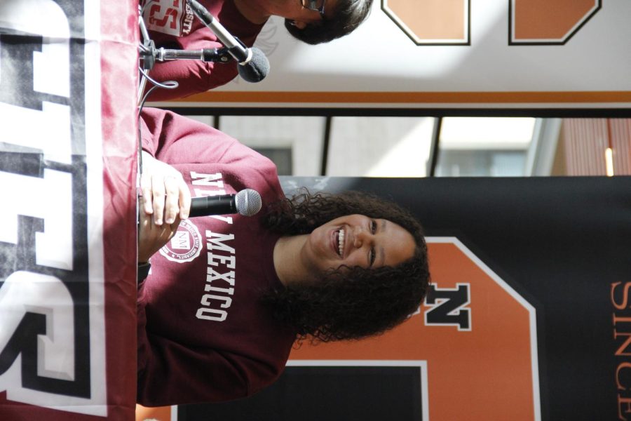 Alesha lane wears a maroon Aggies shirt while sitting in front of her NC high school logo