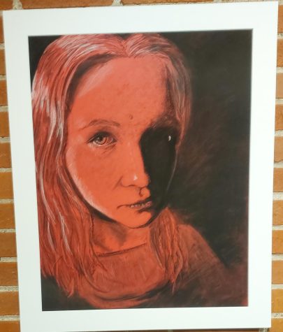 Charcoal portrait of a young girl on red toned paper.