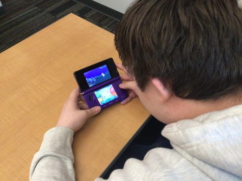 student plays pokemon on gaming device