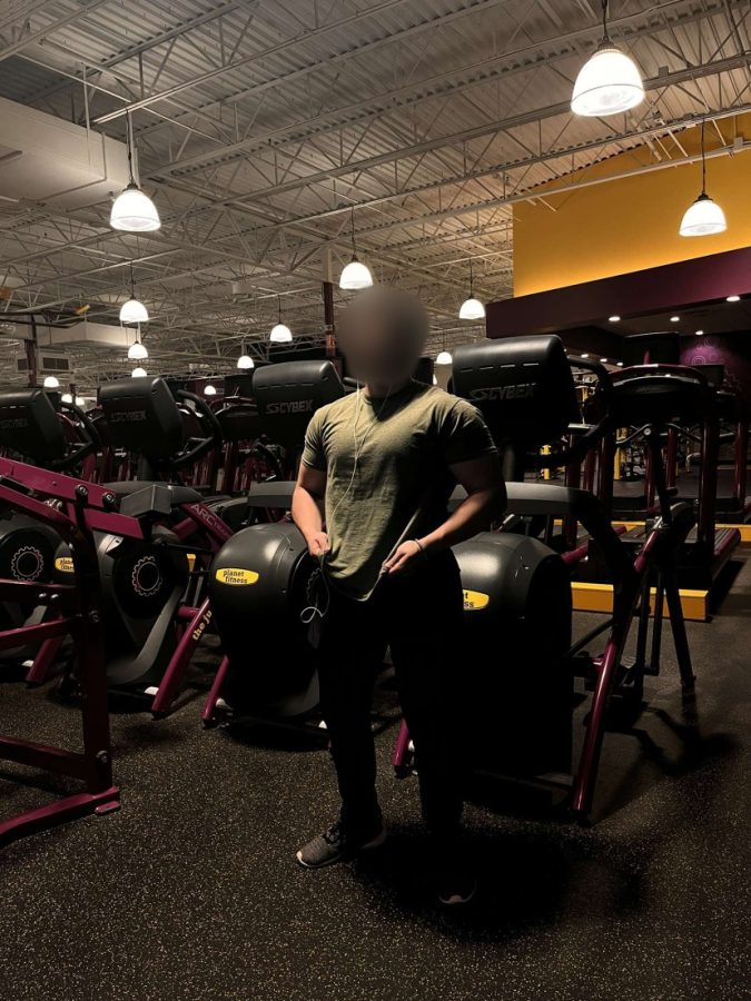 Person standing in gym with weights showing behind him.