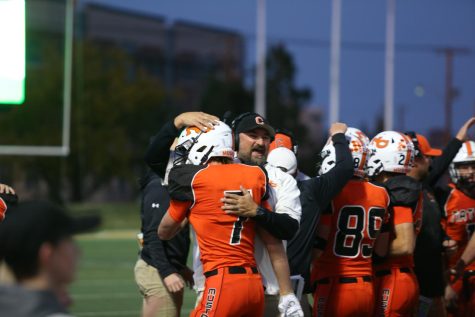 Football coach patting helmet of player in orange